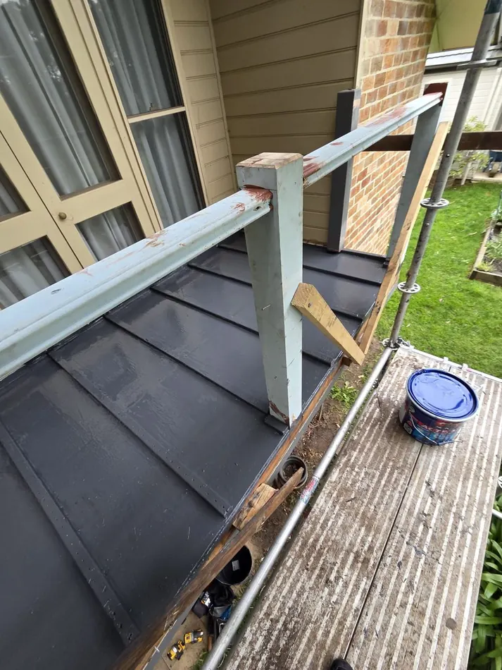 Damaged balcony railing and roofing before restoration